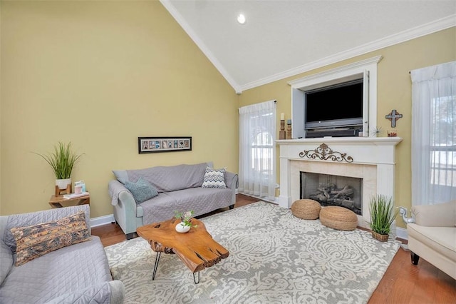 living room with a tile fireplace, wood-type flooring, vaulted ceiling, and ornamental molding