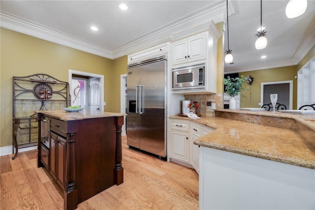 kitchen featuring crown molding, white cabinetry, hanging light fixtures, dark brown cabinets, and built in appliances