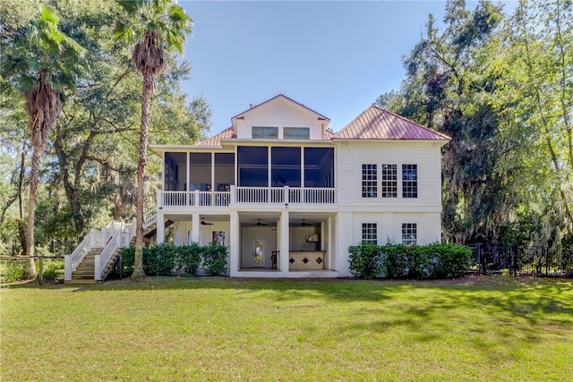 back of property featuring ceiling fan, a patio, a sunroom, and a lawn