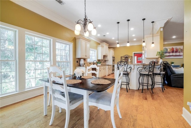 dining area featuring crown molding, an inviting chandelier, and light hardwood / wood-style floors