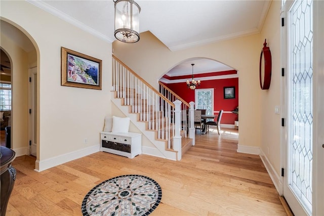 foyer with hardwood / wood-style flooring, crown molding, and an inviting chandelier