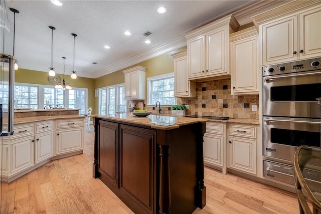 kitchen featuring hanging light fixtures, a center island, black electric stovetop, light stone countertops, and stainless steel double oven