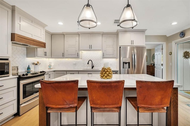 246 Alabama St, Saint Simons Island, GA 31522 - kitchen with appliances with stainless steel finishes, a sink, a center island, light wood-type flooring, and backsplash