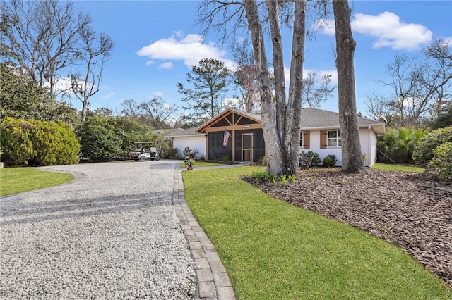 246 Alabama St, Saint Simons Island, GA 31522 - single story home featuring gravel driveway, a front yard, a sunroom, and stucco siding