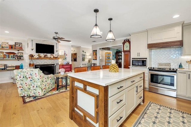 246 Alabama St, Saint Simons Island, GA 31522 - kitchen with appliances with stainless steel finishes, a ceiling fan, light wood finished floors, a fireplace, and recessed lighting