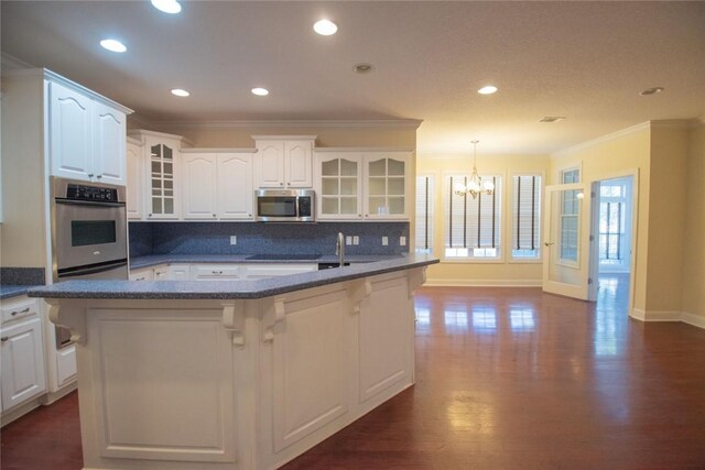 kitchen with sink, ornamental molding, an island with sink, decorative backsplash, and white cabinets