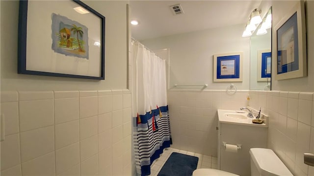 full bathroom with visible vents, tile walls, wainscoting, tile patterned floors, and toilet