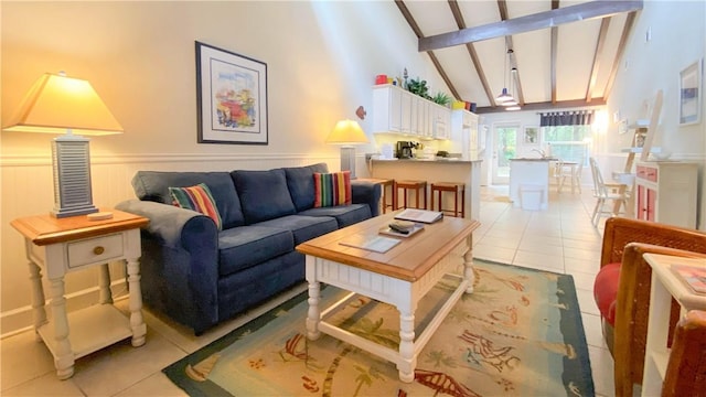 living room featuring beamed ceiling, high vaulted ceiling, light tile patterned floors, and a wainscoted wall