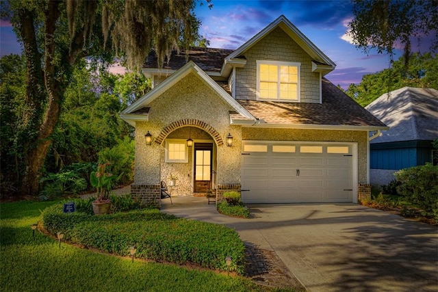 107 Reynoso Ave, Saint Simons Island, GA 31522 - view of front facade with driveway, a garage, brick siding, and roof with shingles