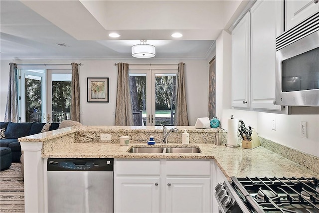 kitchen with appliances with stainless steel finishes, white cabinetry, a wealth of natural light, and sink