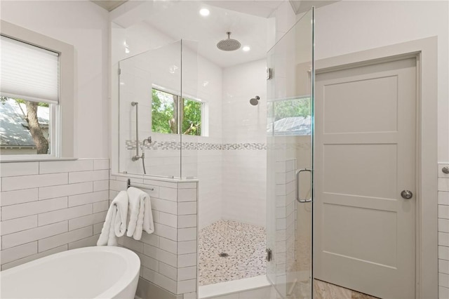 full bath featuring a stall shower, tile walls, a freestanding tub, and a wealth of natural light