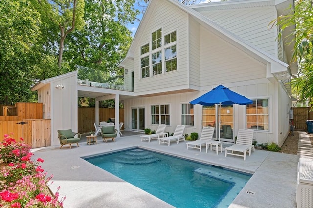 rear view of property with fence, a fenced in pool, board and batten siding, and a patio area