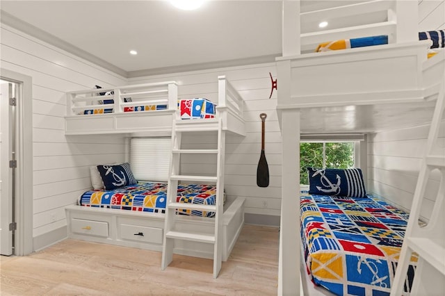 bedroom with wooden walls and light wood-style floors