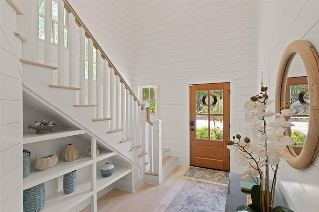 foyer entrance with wood finished floors, stairs, and a towering ceiling