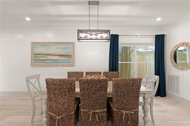 dining area featuring recessed lighting, light wood-type flooring, visible vents, wood walls, and ornamental molding