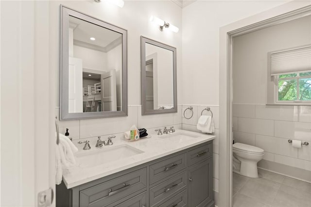 bathroom with toilet, tile walls, a sink, and tile patterned flooring