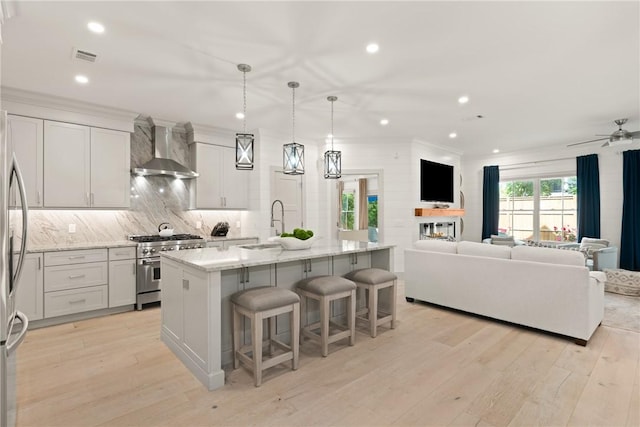 kitchen with wall chimney exhaust hood, a kitchen breakfast bar, open floor plan, and stainless steel appliances