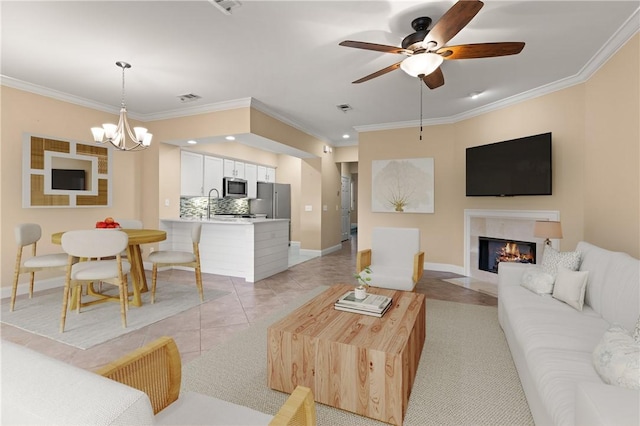 living area with crown molding, baseboards, and ceiling fan with notable chandelier