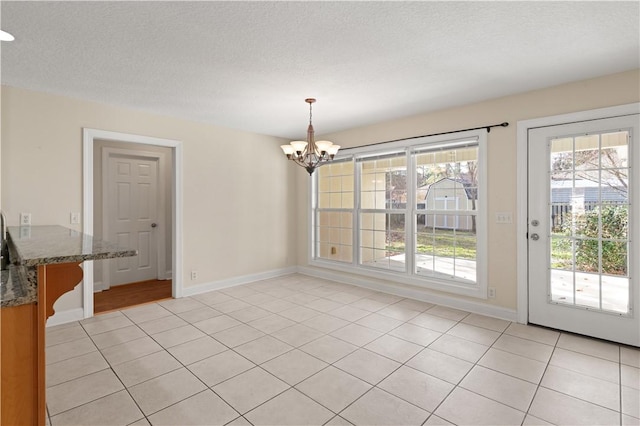 unfurnished dining area with light tile patterned floors, a textured ceiling, and a notable chandelier