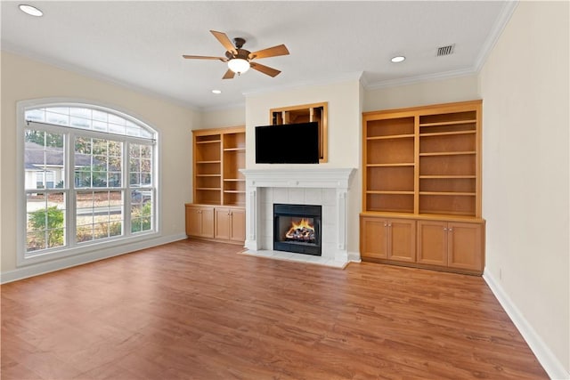 unfurnished living room with a tile fireplace, light hardwood / wood-style flooring, ceiling fan, and crown molding