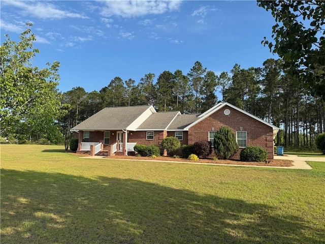view of front facade with a porch, brick siding, and a front yard