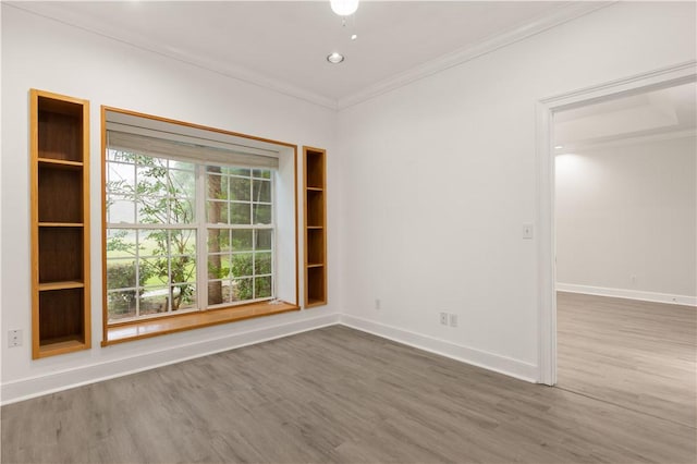 spare room with ornamental molding, wood finished floors, and baseboards