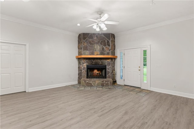 unfurnished living room with wood finished floors, crown molding, a stone fireplace, ceiling fan, and baseboards