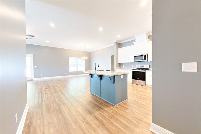 550 Freedom Trl, Brunswick, GA 31525 - kitchen with a kitchen bar, stainless steel appliances, a kitchen island with sink, white cabinets, and light hardwood / wood-style floors