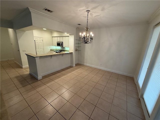 kitchen featuring kitchen peninsula, crown molding, white cabinets, a chandelier, and hanging light fixtures