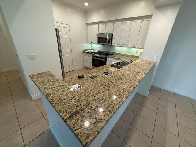 kitchen with kitchen peninsula, stainless steel appliances, sink, light tile patterned floors, and white cabinetry