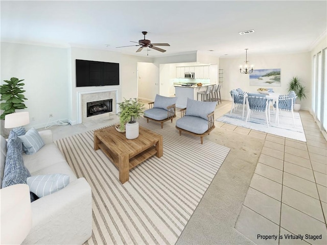 living room with visible vents, baseboards, a fireplace with flush hearth, light tile patterned floors, and ceiling fan with notable chandelier