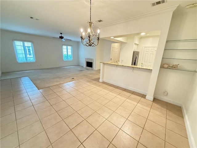 kitchen with ceiling fan with notable chandelier, light stone countertops, decorative light fixtures, a kitchen bar, and stainless steel refrigerator