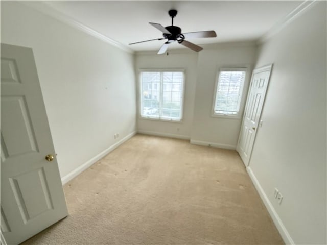 carpeted spare room with ceiling fan and crown molding