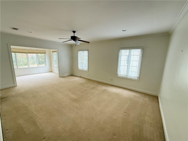 spare room featuring ceiling fan, light colored carpet, and ornamental molding