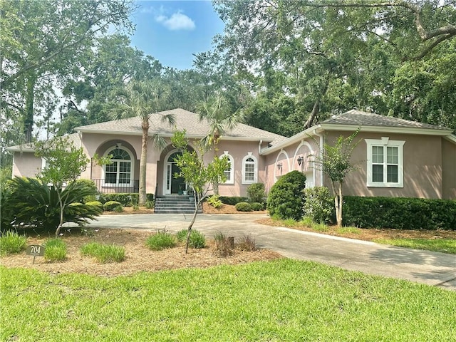 704 Dungeness, Saint Simons Island, GA 31522 - mediterranean / spanish house with stucco siding, a front lawn, concrete driveway, and covered porch