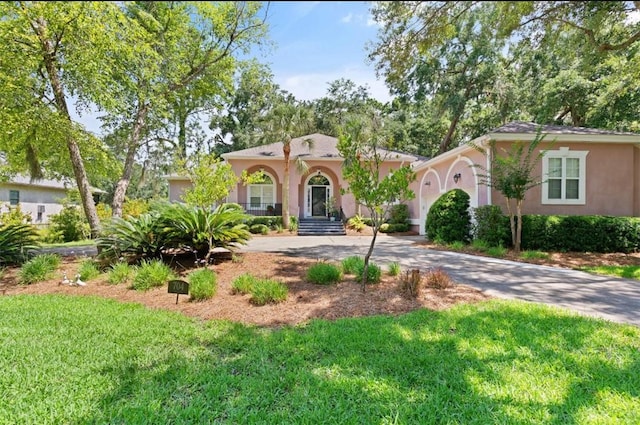 704 Dungeness, Saint Simons Island, GA 31522 - mediterranean / spanish home with stucco siding, driveway, a front lawn, and a garage