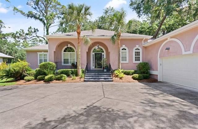 704 Dungeness, Saint Simons Island, GA 31522 - view of front of house with concrete driveway, stucco siding, a garage, and covered porch