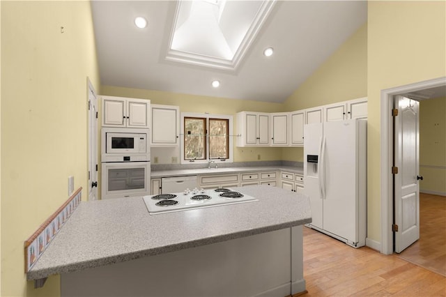 kitchen featuring high vaulted ceiling, white appliances, light hardwood / wood-style floors, and white cabinets