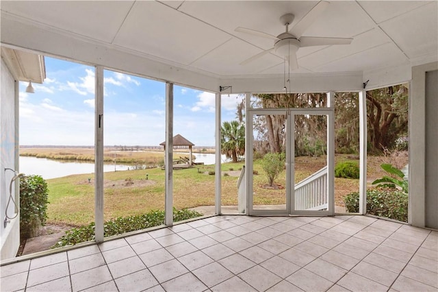 unfurnished sunroom with ceiling fan and a water view