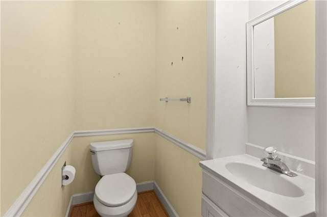 bathroom featuring toilet, wood-type flooring, and vanity