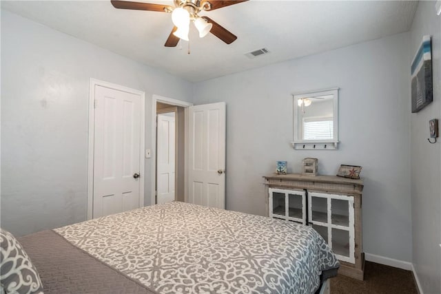 carpeted bedroom with a ceiling fan, visible vents, and baseboards