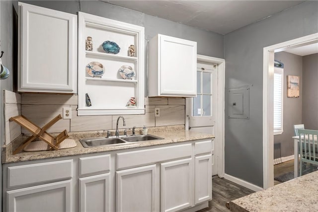 kitchen with tasteful backsplash, dark wood-type flooring, white cabinets, a sink, and baseboards