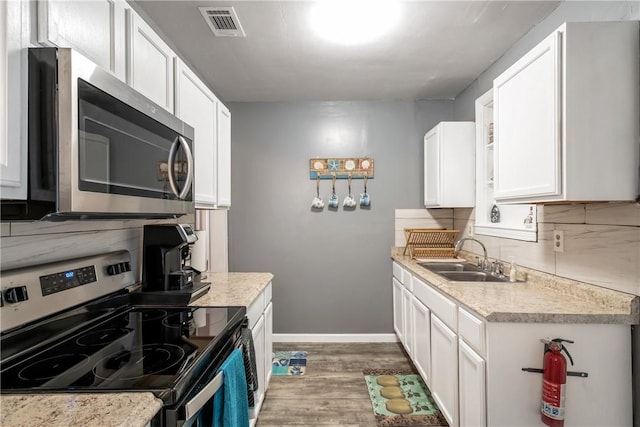 kitchen with tasteful backsplash, light countertops, appliances with stainless steel finishes, white cabinetry, and a sink