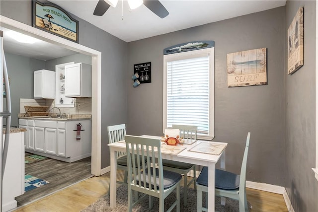 dining space featuring light wood-style flooring, baseboards, and ceiling fan