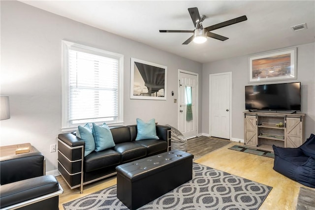 living area featuring light wood-style floors, ceiling fan, visible vents, and baseboards