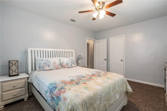 bedroom with ceiling fan, visible vents, baseboards, a closet, and dark colored carpet