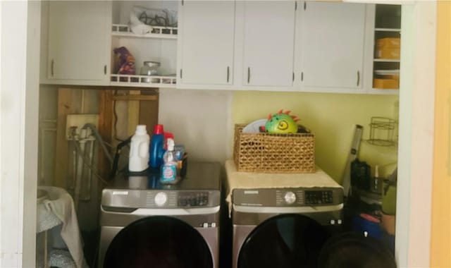 clothes washing area featuring washer and clothes dryer and cabinets