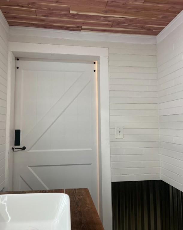 bathroom with wooden ceiling and wooden walls