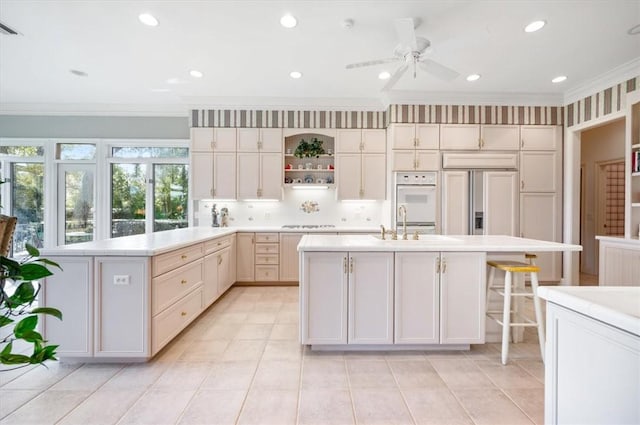 kitchen with white double oven, paneled built in fridge, crown molding, and an island with sink