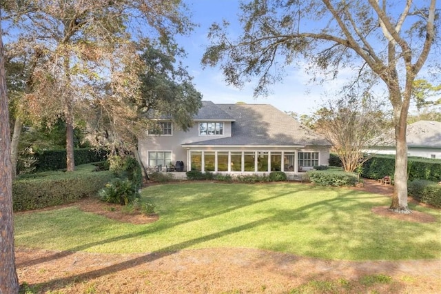 back of property with a sunroom and a yard